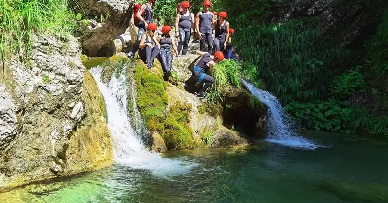 Grupa u kacigama pored vodopada i zelenog bazena